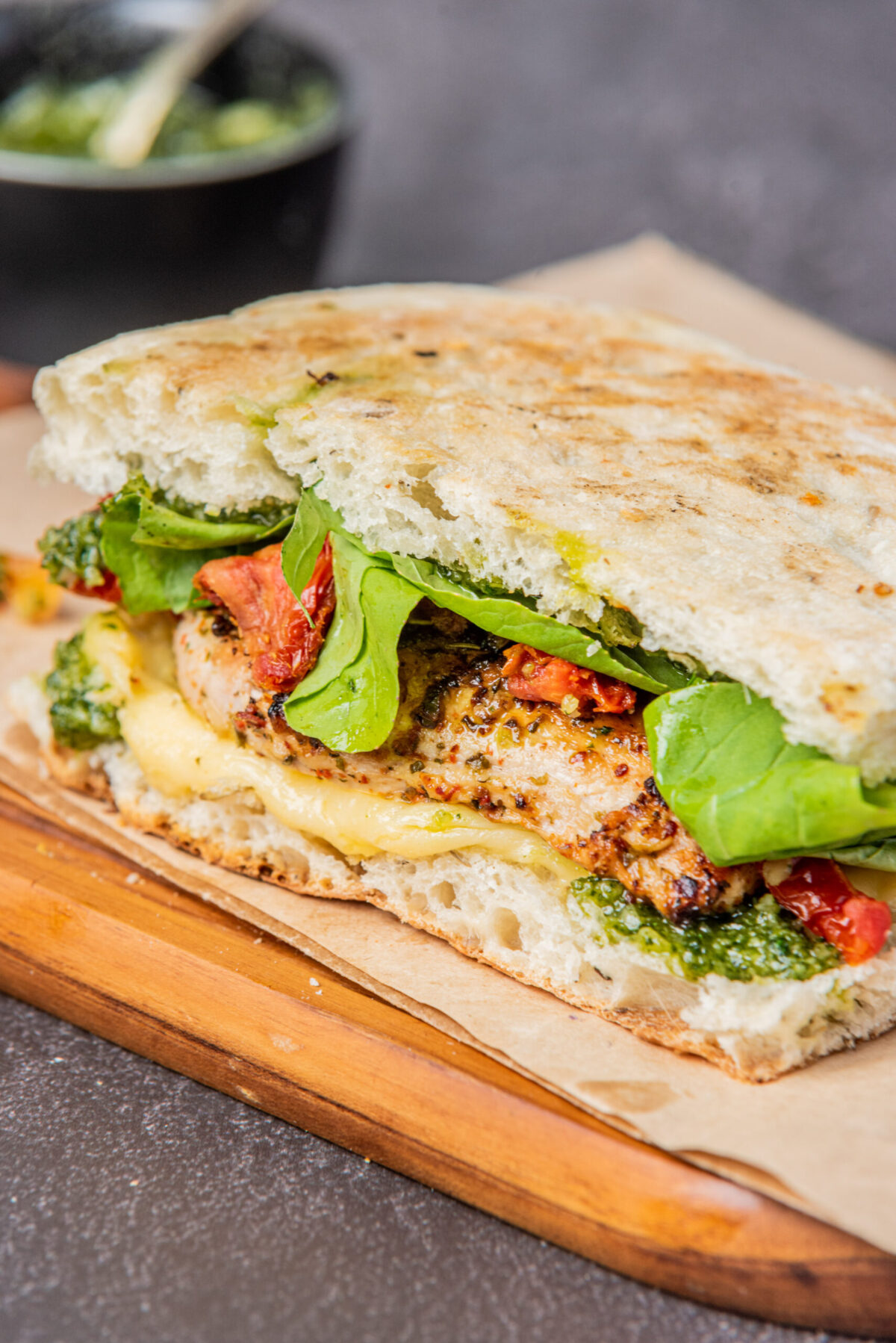 pesto chicken sandwich assembled with arugula on a wood board, close up photo