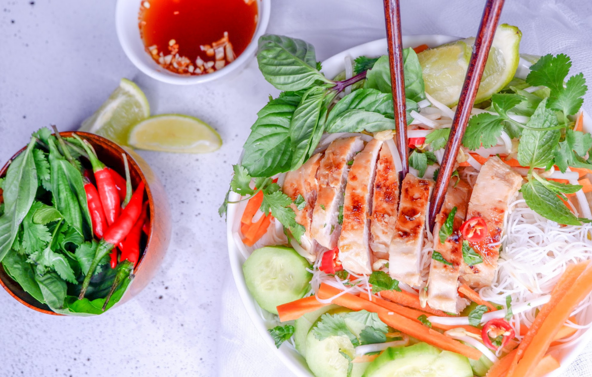 Light lemongrass chicken noodle bowl recipe that will bring you a refreshing twist to your lunch or dinner. Marinated meat, fresh vegetables and tender noodles. #healthy #lemongrass #chicken #ricenoodles #easy #mealprep #recipe #freshvegetables #Vietnamese