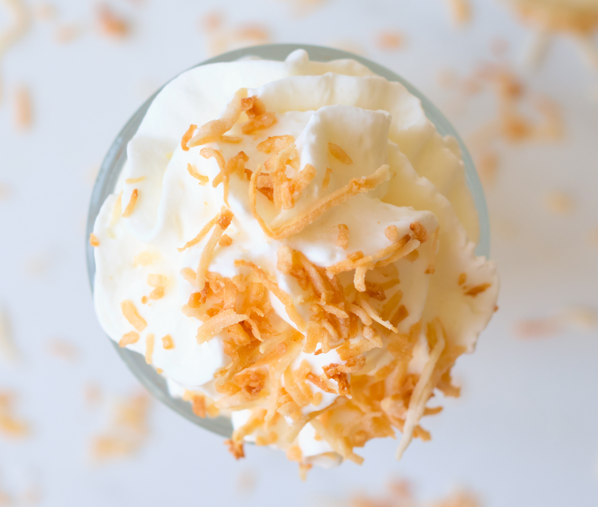 This Coconut Pineapple Italian soda recipe is perfect for any occasion or gathering. They are easy to make and can easily be customized. top view of whipping cream with toasted coconut