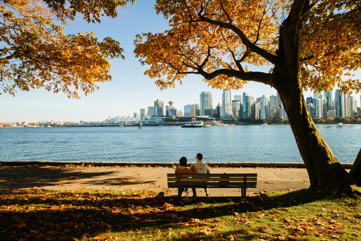 Seawall park bench couple looking across water to downtown Vancouver