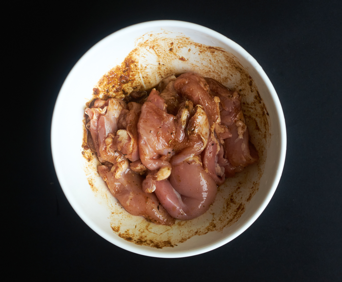 raw chicken thighs in a bowl mixed with the marinade ingredients
