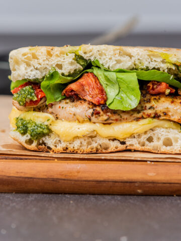 pesto chicken sandwich assembled with arugula on a wood board, close up photo