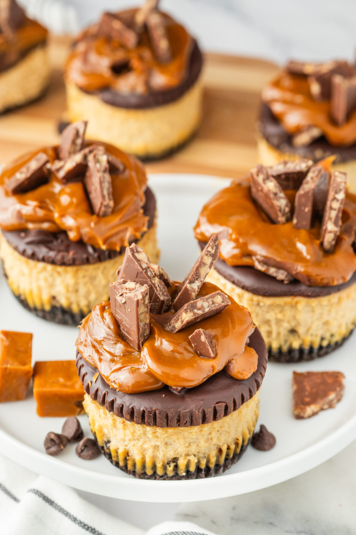 mini cheesecakes on a white plate with caramel and chocolate chips