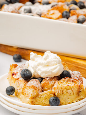 blueberry croissant breakfast bake slice with whipped cream on top.